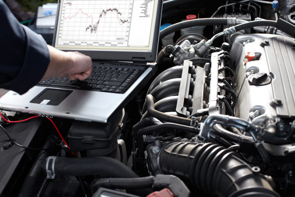 auto repair man working on car and reviewing data on computer