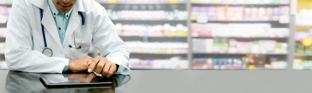 pharmacist looking at tablet computer on pharmacy counter